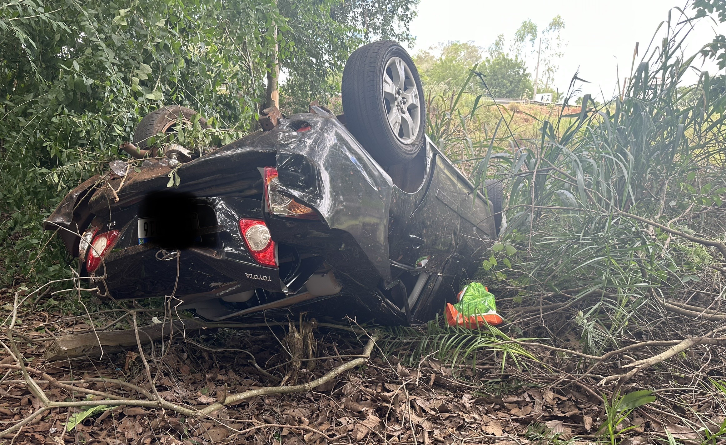 Veículo após capotar parou com as rodas para cima fora da pista